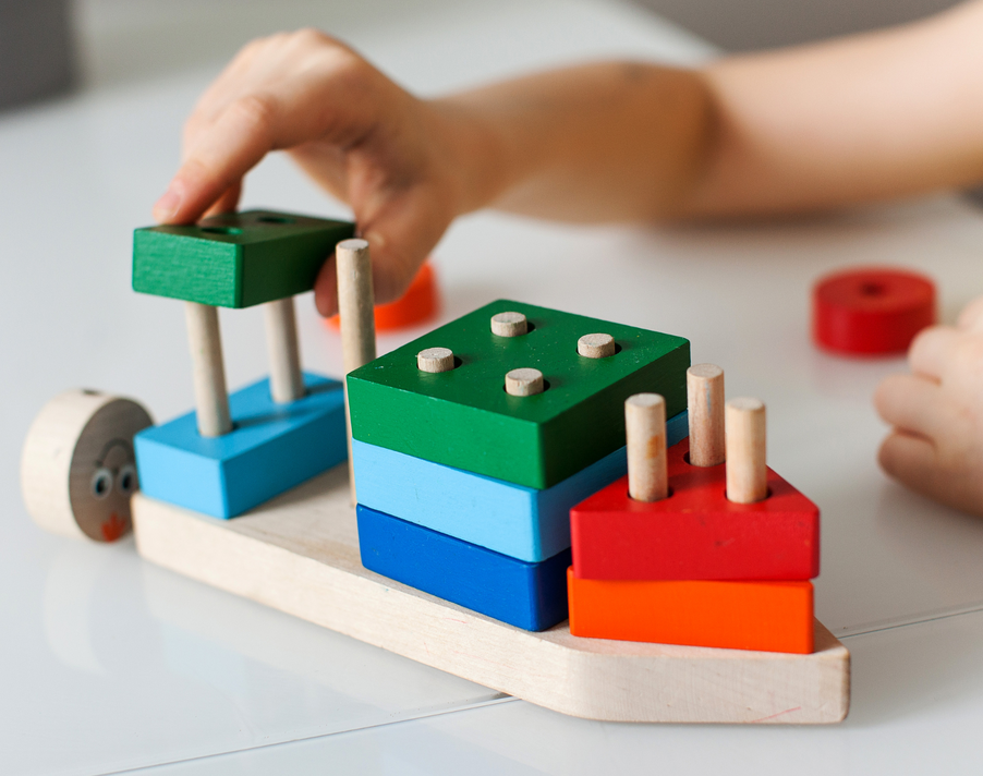 A child is playing with a wooden toy on a table.