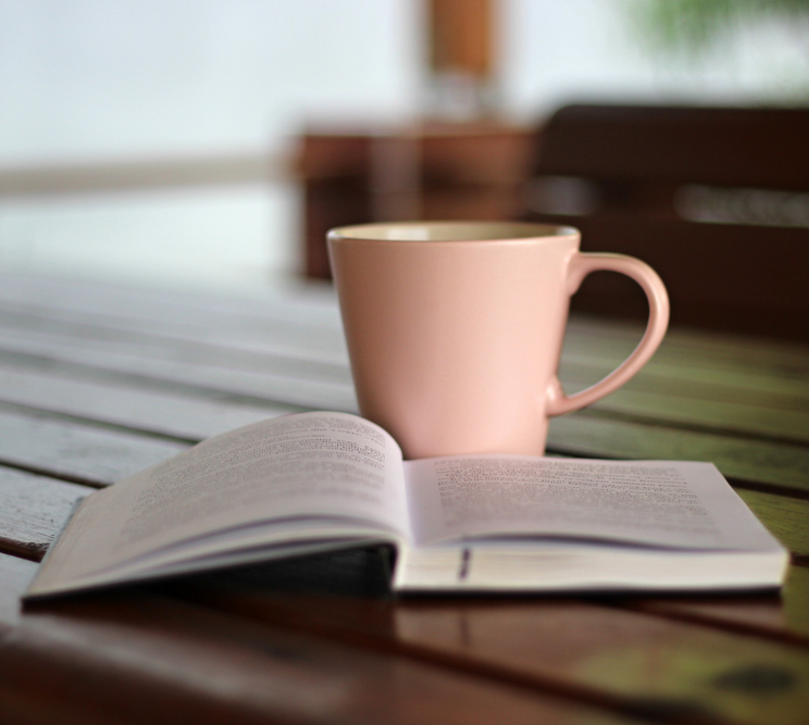 A pink cup sits on top of an open book