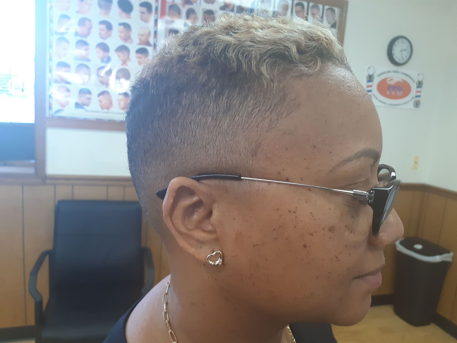 A woman with short hair and glasses is sitting in a chair.