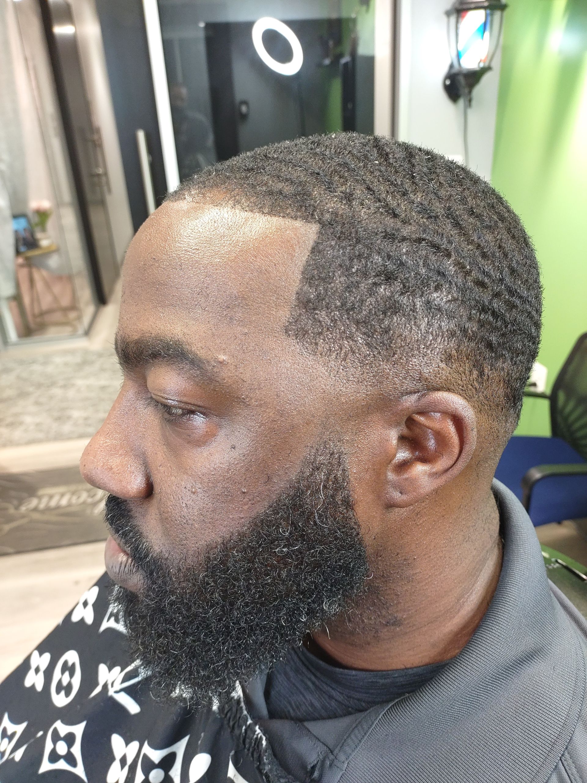 A man with a beard is getting his hair cut at a barber shop.