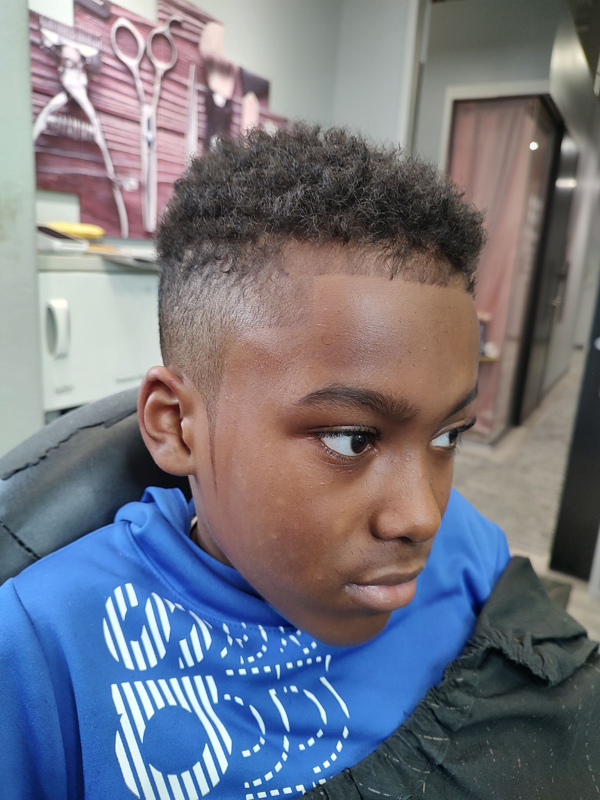 A young boy is getting his hair cut at a barber shop