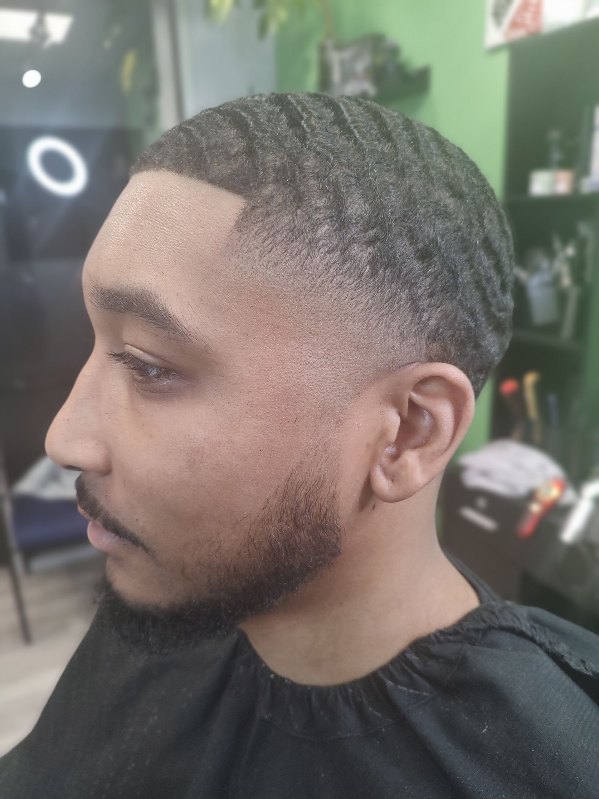 A man with a beard is getting his hair cut at a barber shop.
