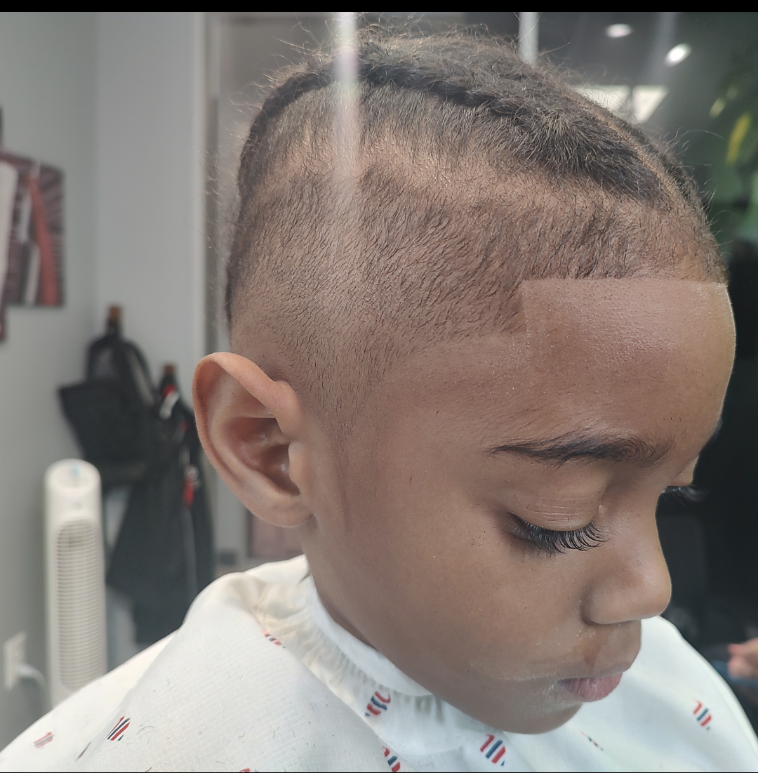 A young boy is getting his hair cut at a barber shop.