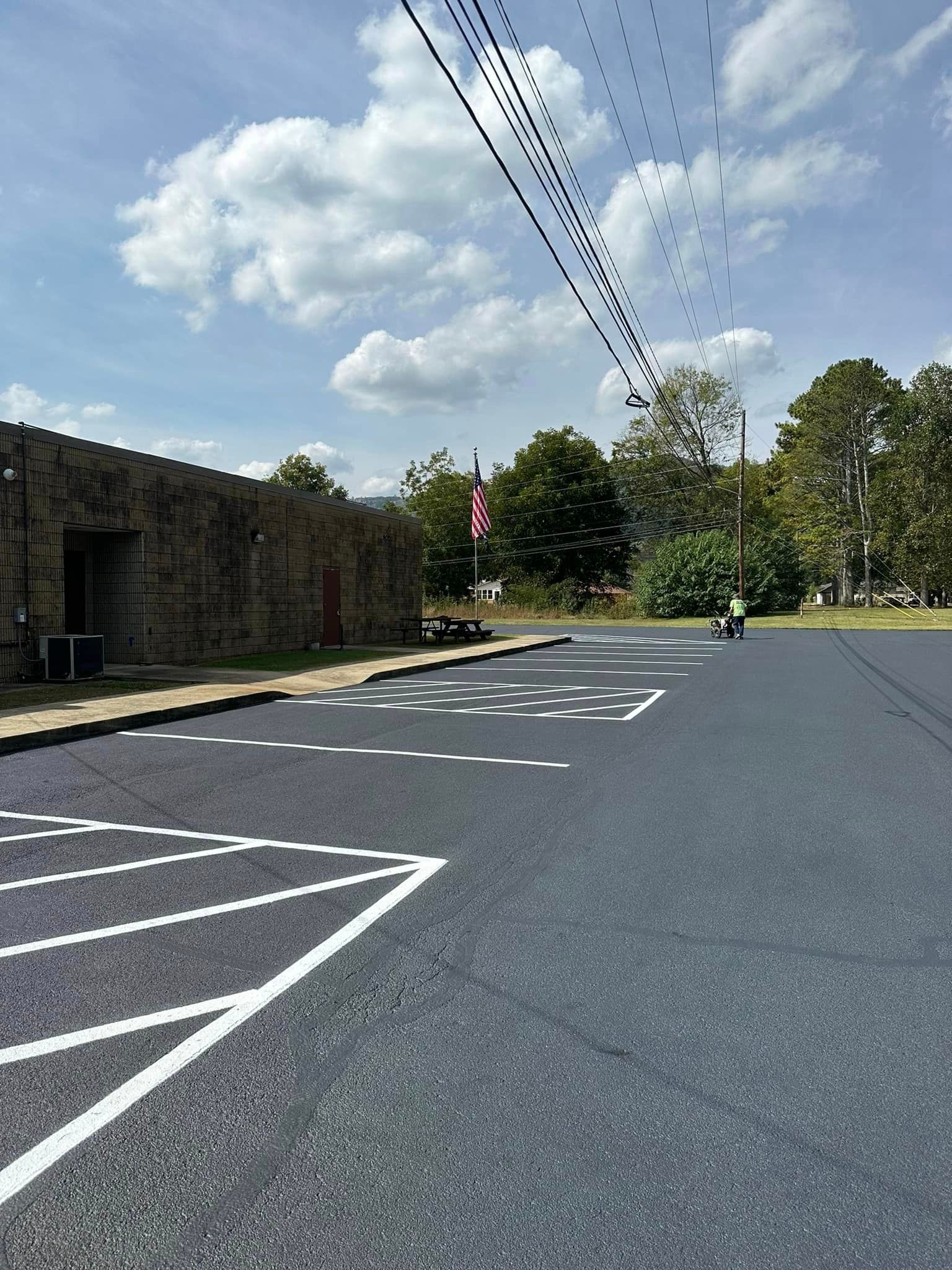 a parking lot with a building in the background and a flag on the side of the road.