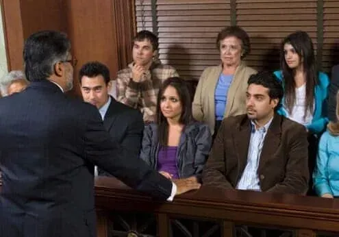Courtroom scene with a judge addressing seated attendees and lawyers during a hearing