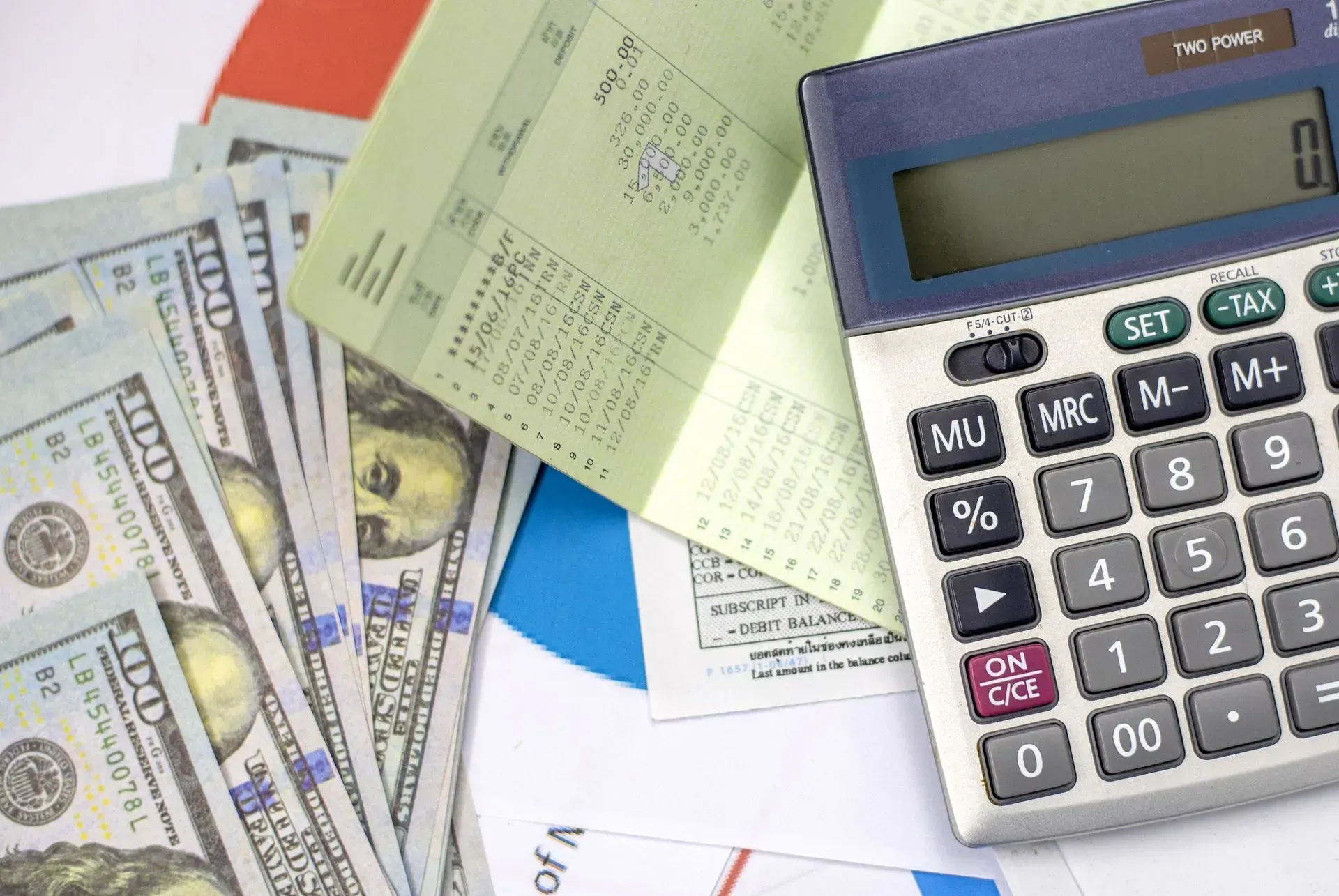 Calculator beside scattered bills and paperwork on a desk