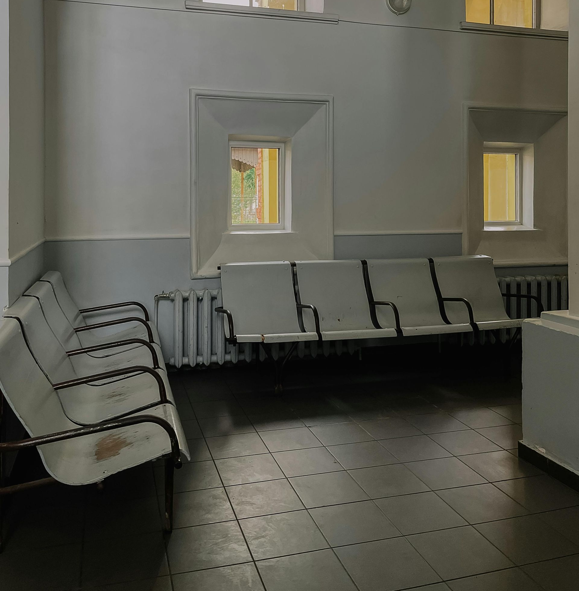 Waiting room with metal benches, tile floor, and small windows.