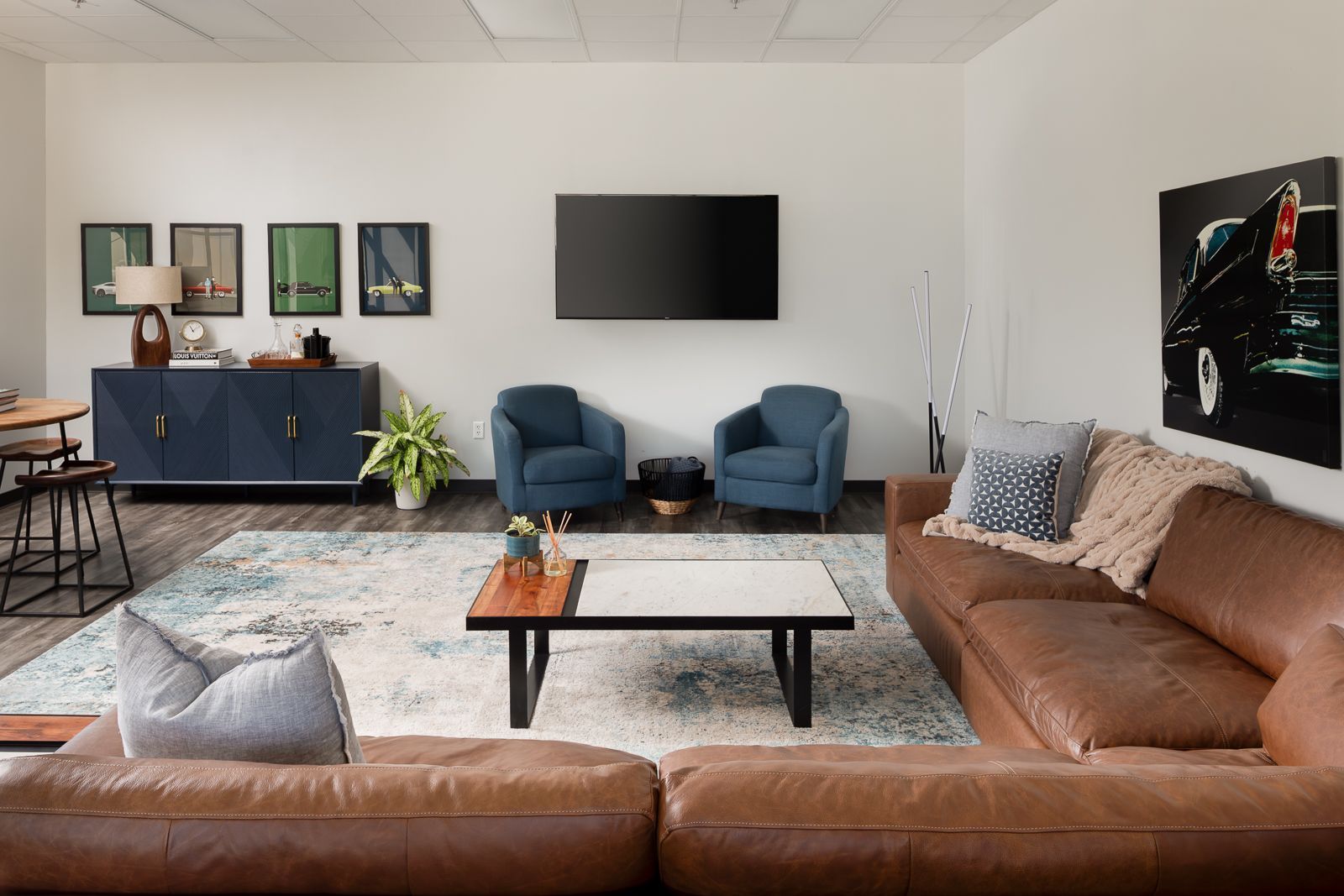 Clubhouse lounge at The Lux with a leather sectional, armchairs and a wall-mounted TV