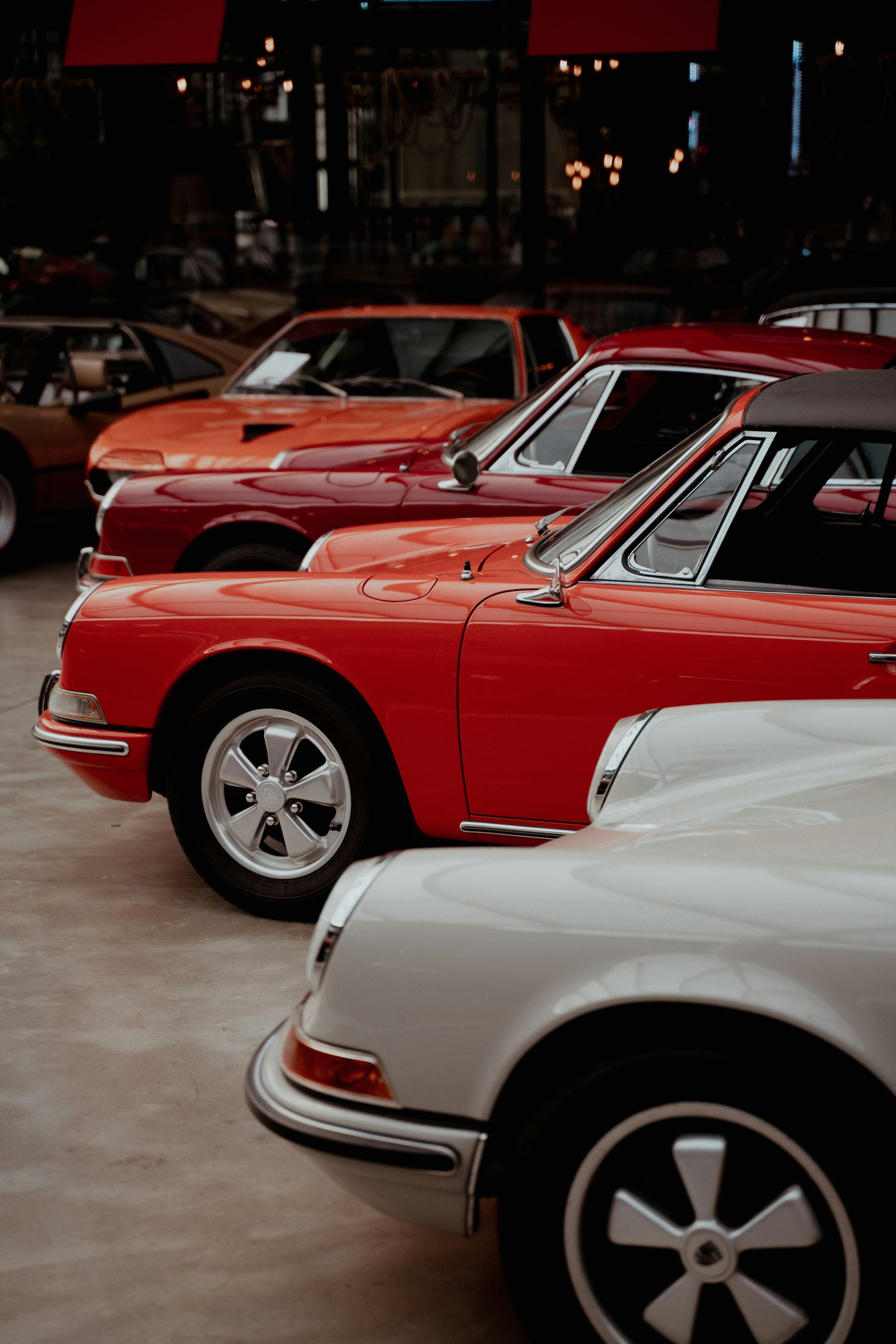 Row of classic Porsche 911s in red and white parked indoors