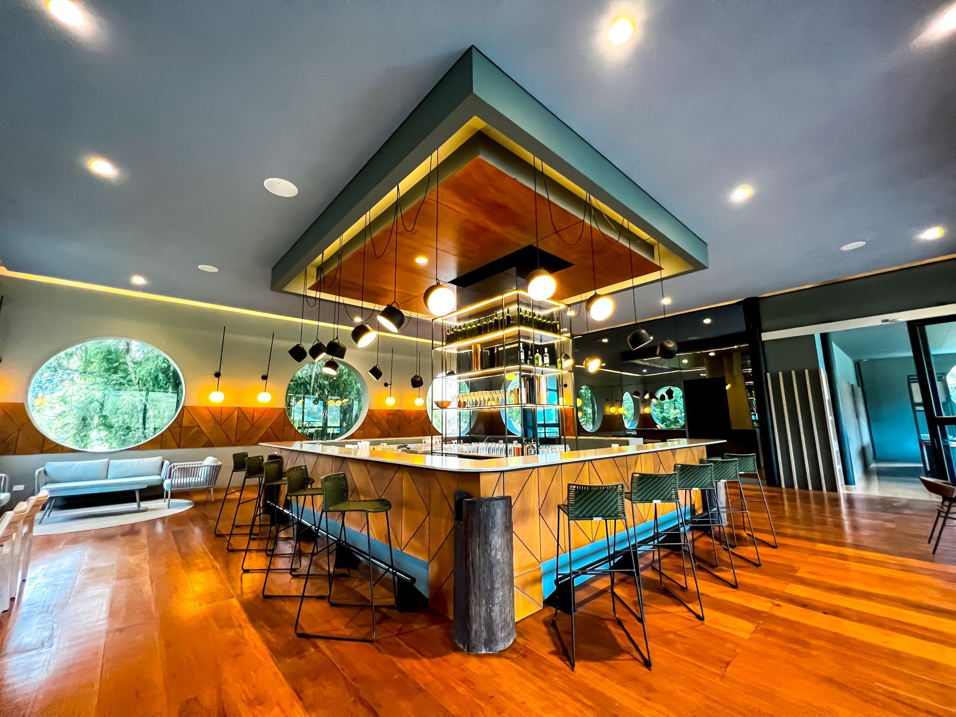 Interior de restaurante con barra central, mesas y piso de madera en Termales El Otoño, hotel con restaurante en Manizales.