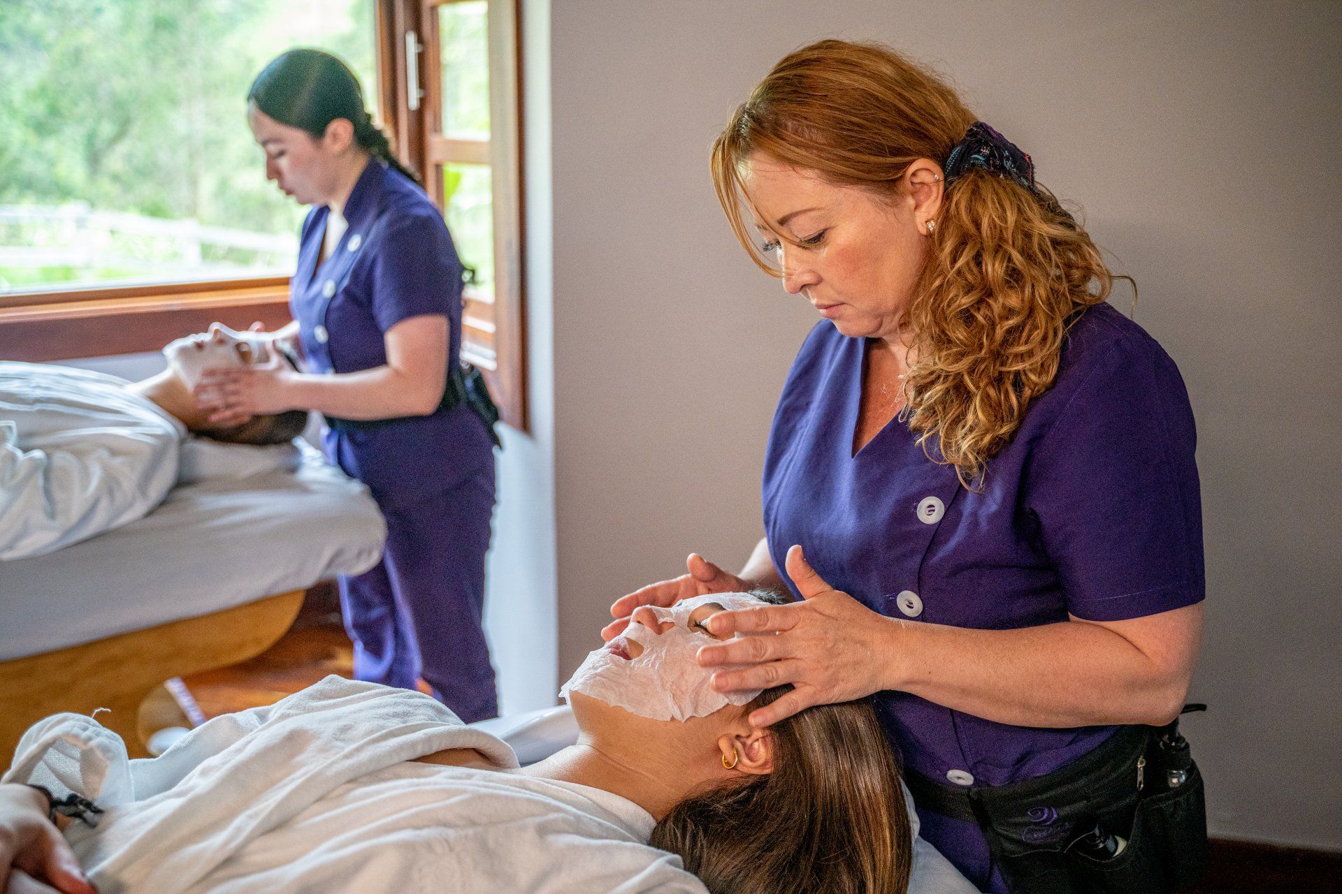 Specialists applying facial treatments to two guests at a spa hotel near Manizales.