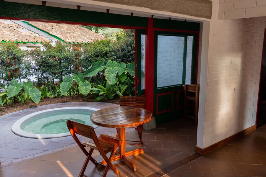 Terraza privada con mesa de madera y jacuzzi exterior en el Hotel Termales El Otoño.
