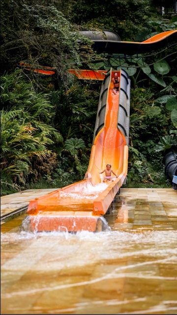 Niño descendiendo por tobogán acuático en el aquaparque Termales El Otoño Manizales, zona de diversión rodeada de selva.