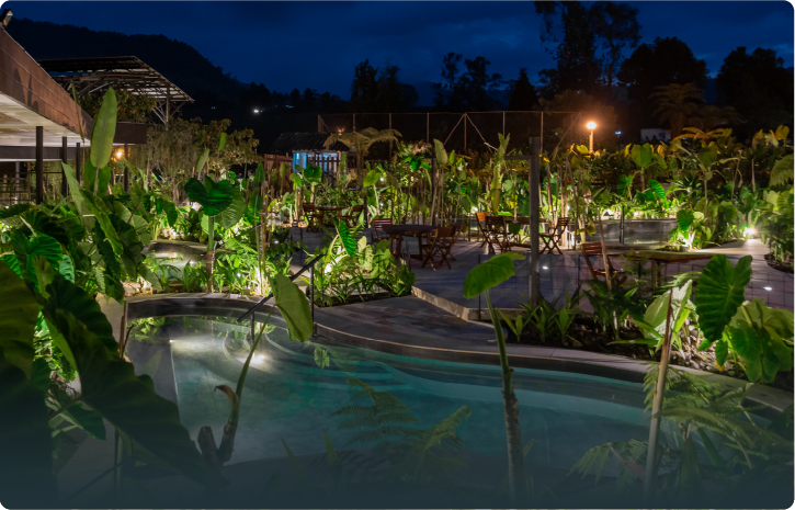 Zona termal nocturna con espejos de agua, senderos y vegetación en Termales El Otoño, hotel con aguas termales en Colombia.