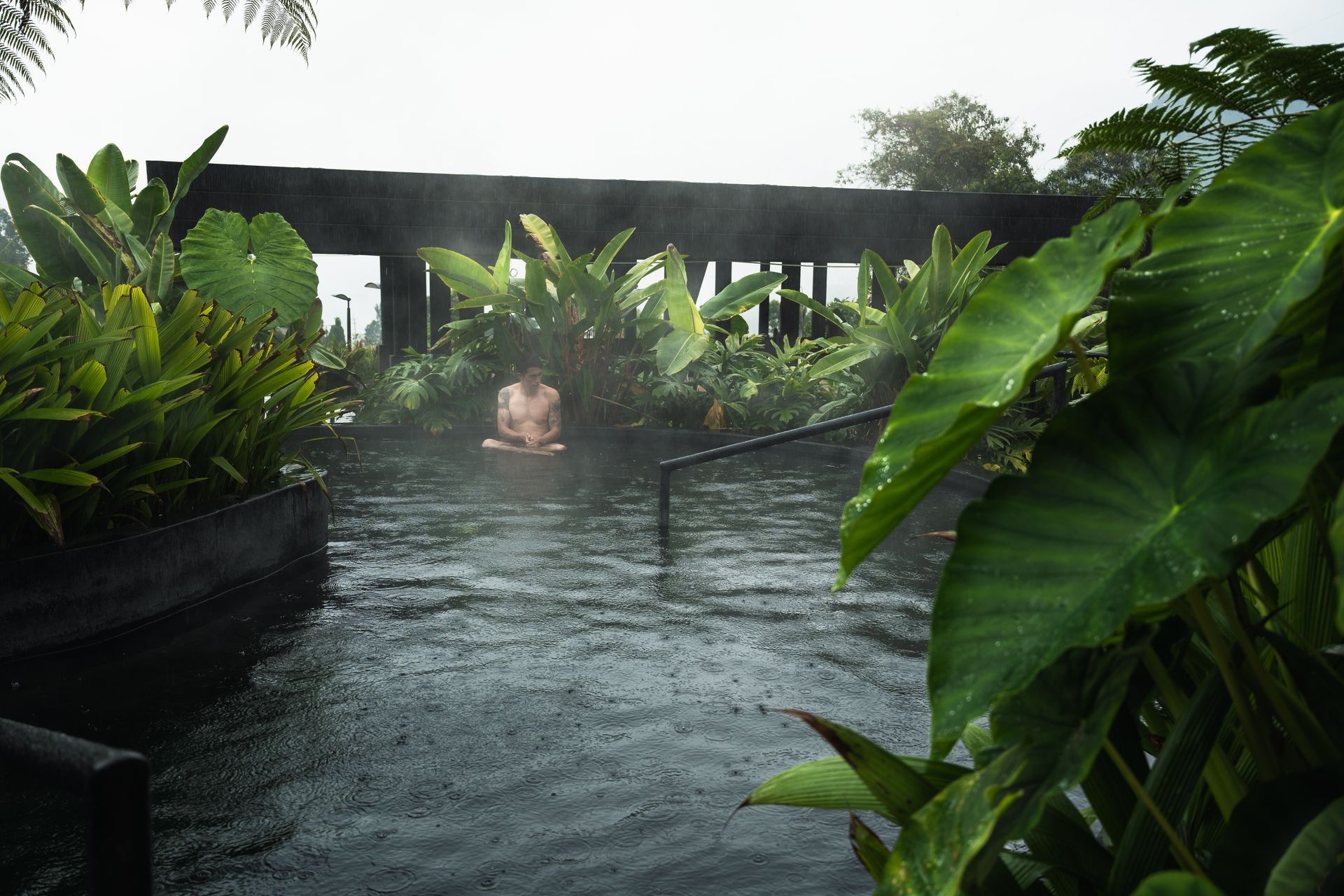 Man relaxing in a thermal pool surrounded by vegetation at Termales El Otoño, a hot springs hotel in Manizales