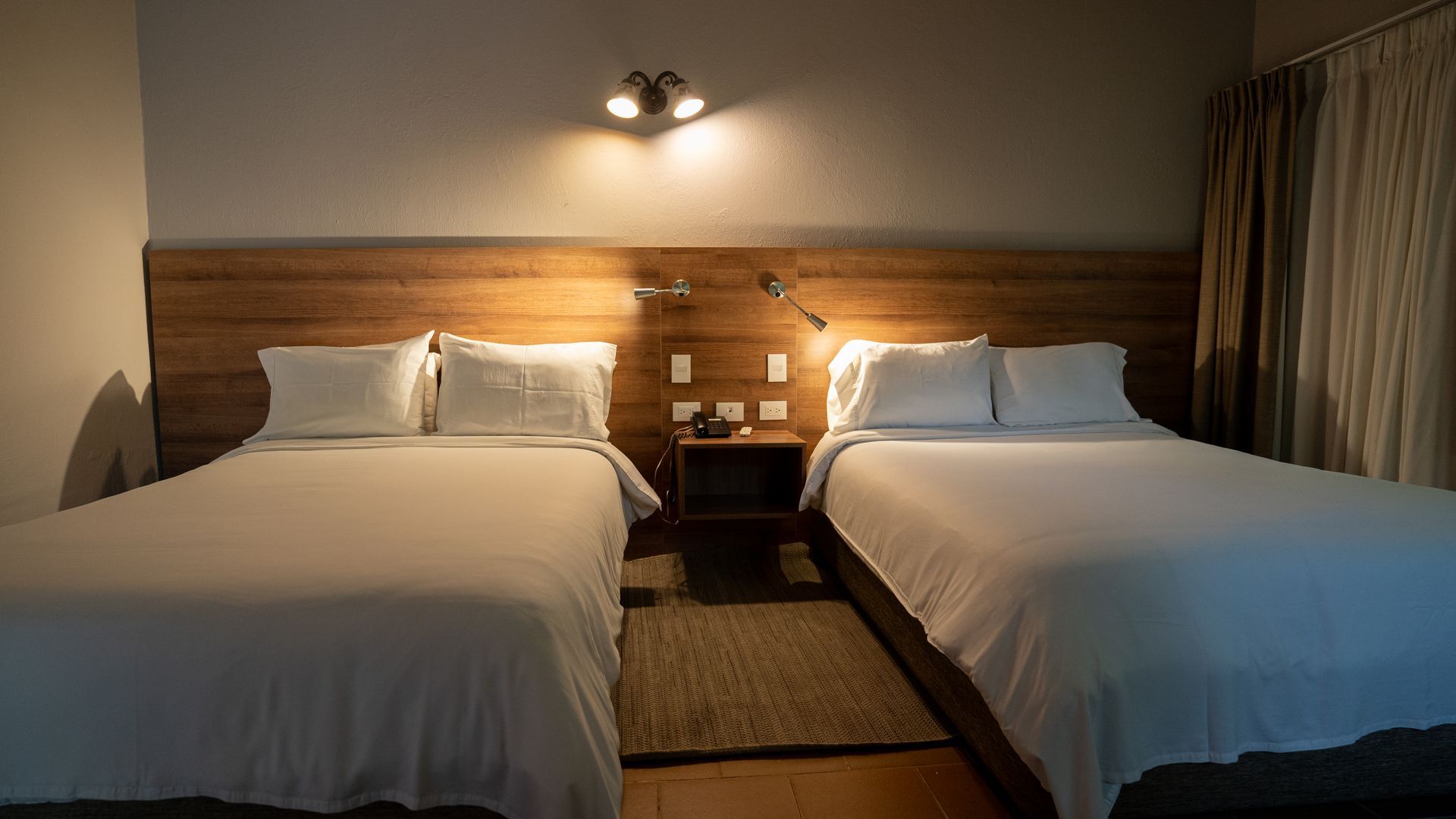 Hotel room with two beds at Termales El Otoño, featuring warm lighting, wooden furniture, and comfortable accommodations