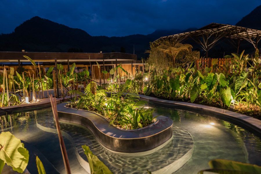 Piscina termal iluminada de noche, rodeada de naturaleza en Termales El Otoño, para vivir las aguas termales en Manizales.