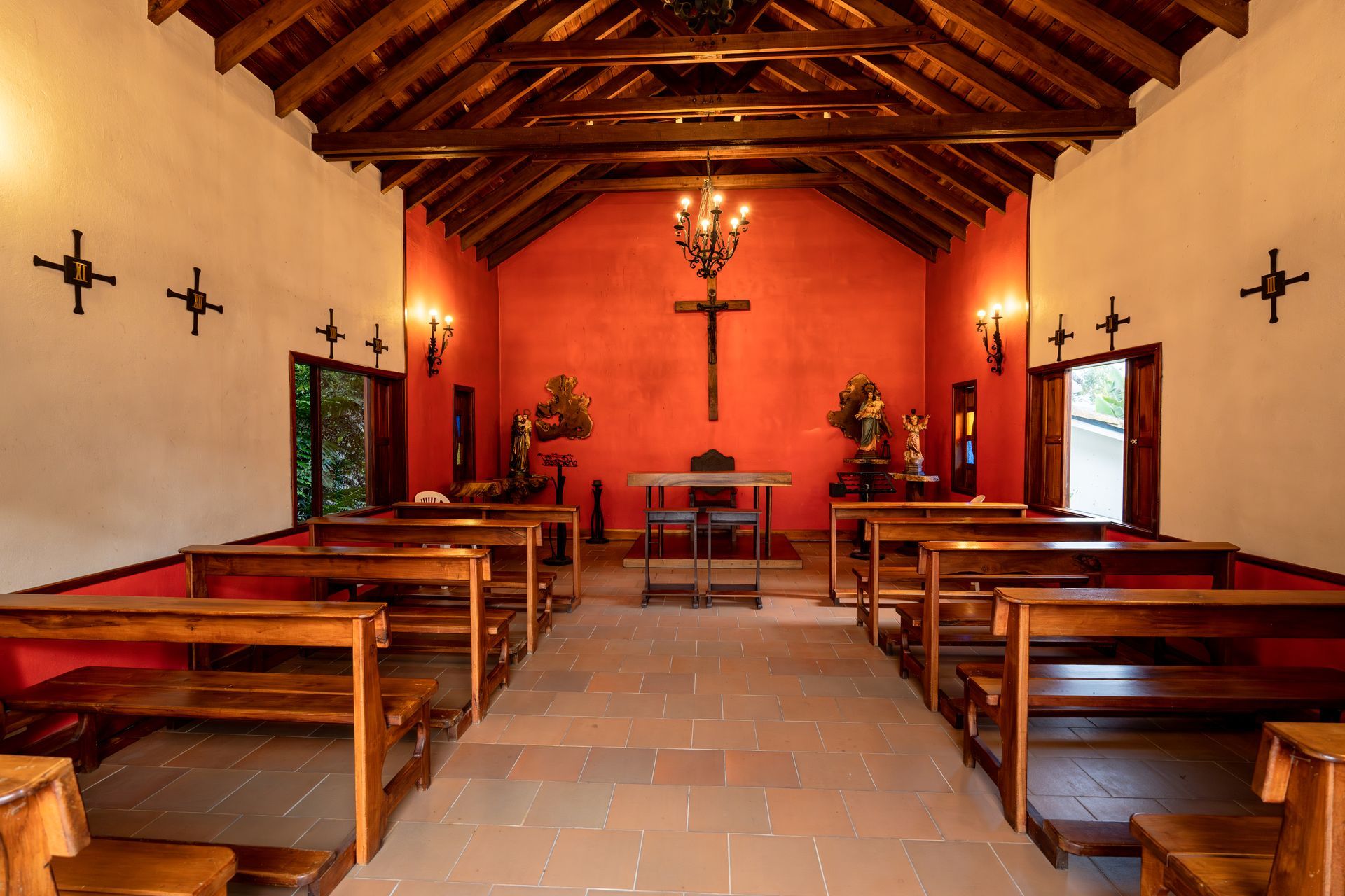 Interior de la Capilla en Termales El Otoño, con altar, bancas de madera, lámpara central y paredes en tono terracota.