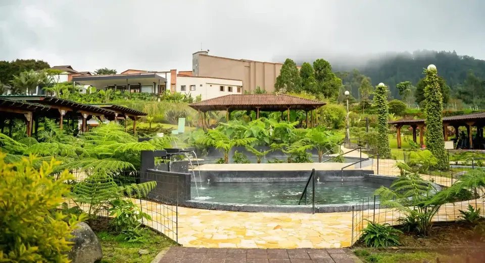 Outdoor thermal pool surrounded by buildings at Termales El Otoño, a hot springs hotel in Manizales.