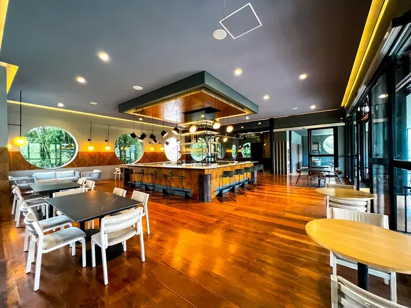 Hotel with a restaurant and bar for events in Manizales, featuring a central bar, tables, chairs, and wooden flooring.