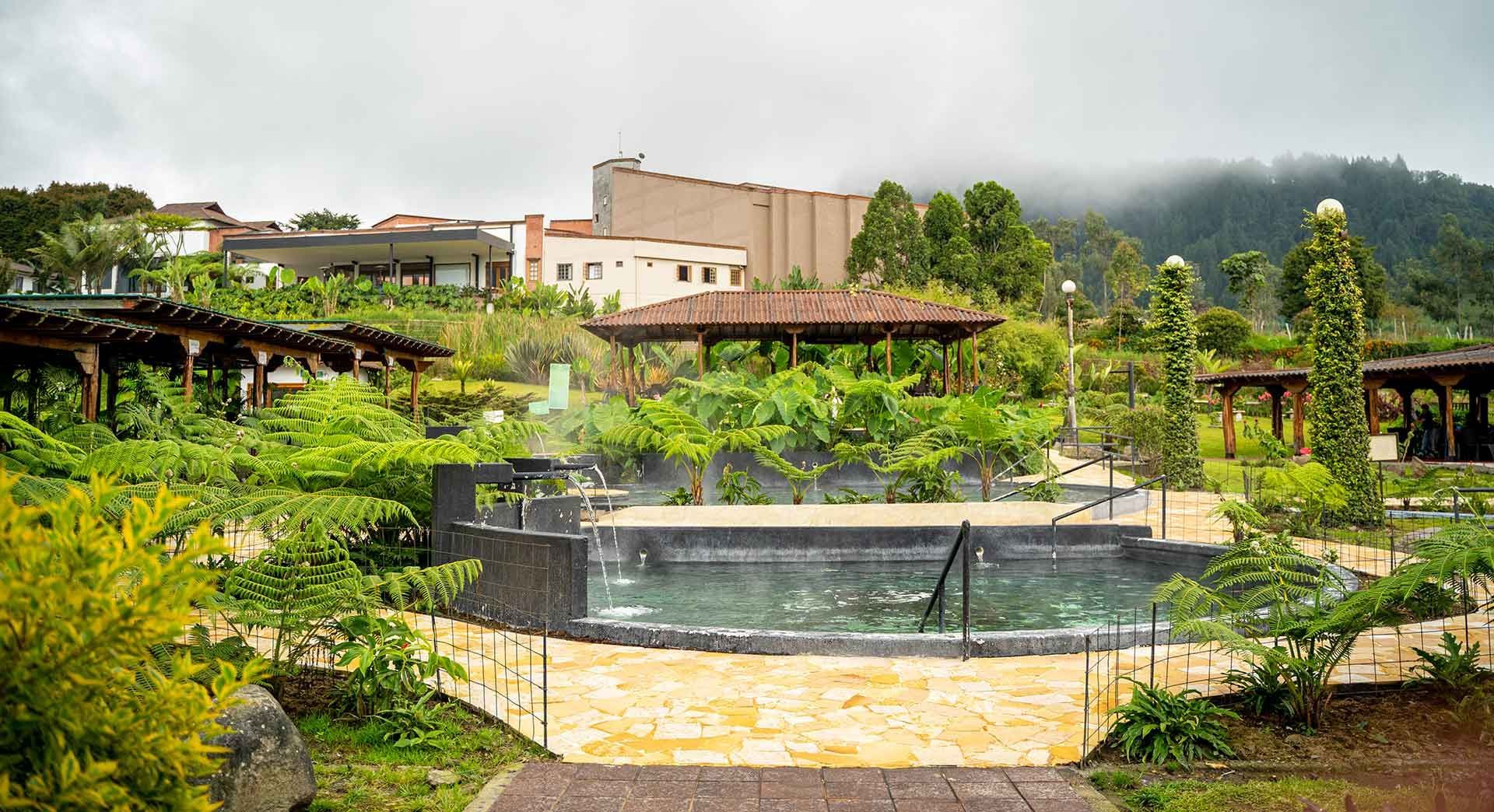 Outdoor thermal pool surrounded by gardens and mountains at Termales El Otoño.