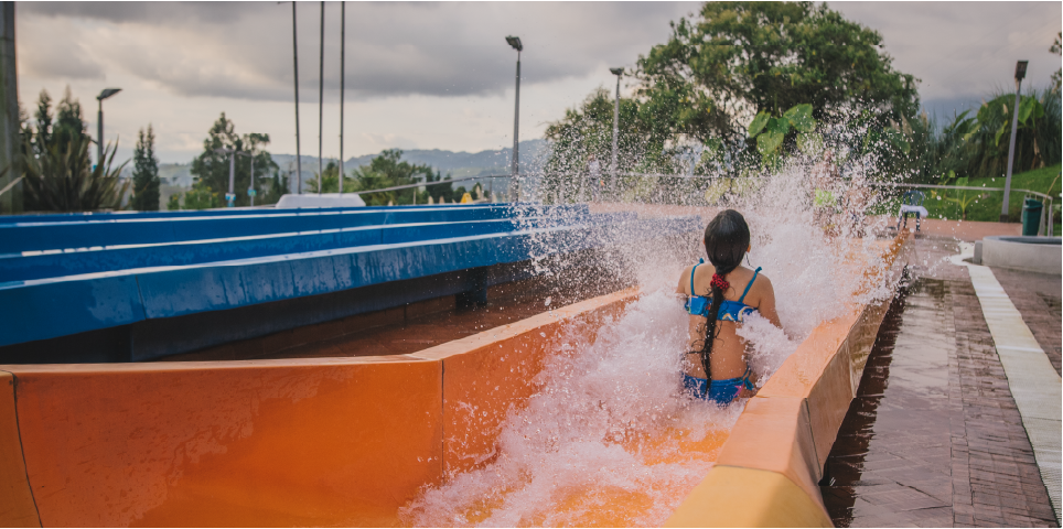 Girl sliding down an orange water slide at Acuaparque Termales El Otoño, a great plan for what to do in Manizales with kids.