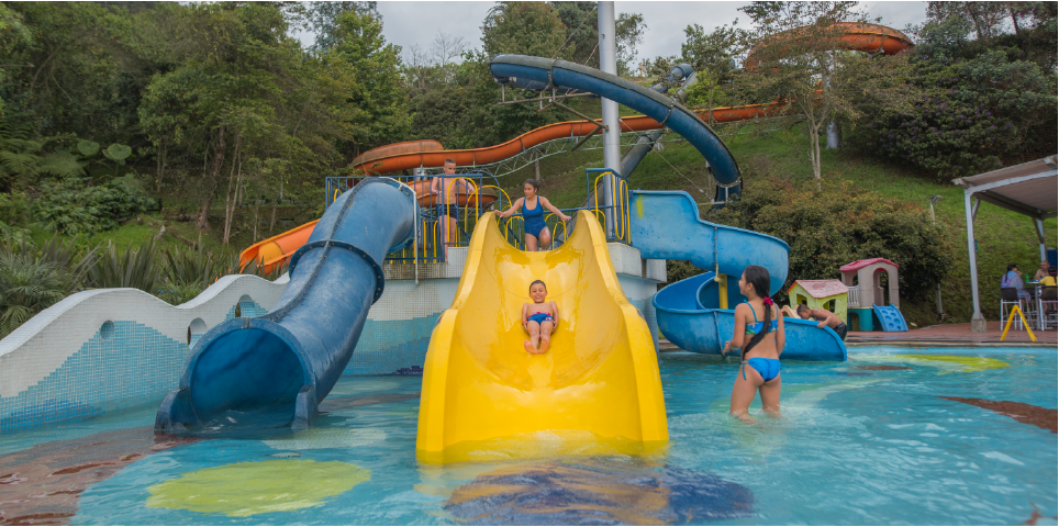 Children enjoying slides and the pool at Acuaparque Termales El Otoño, hot springs in Manizales with water slides.