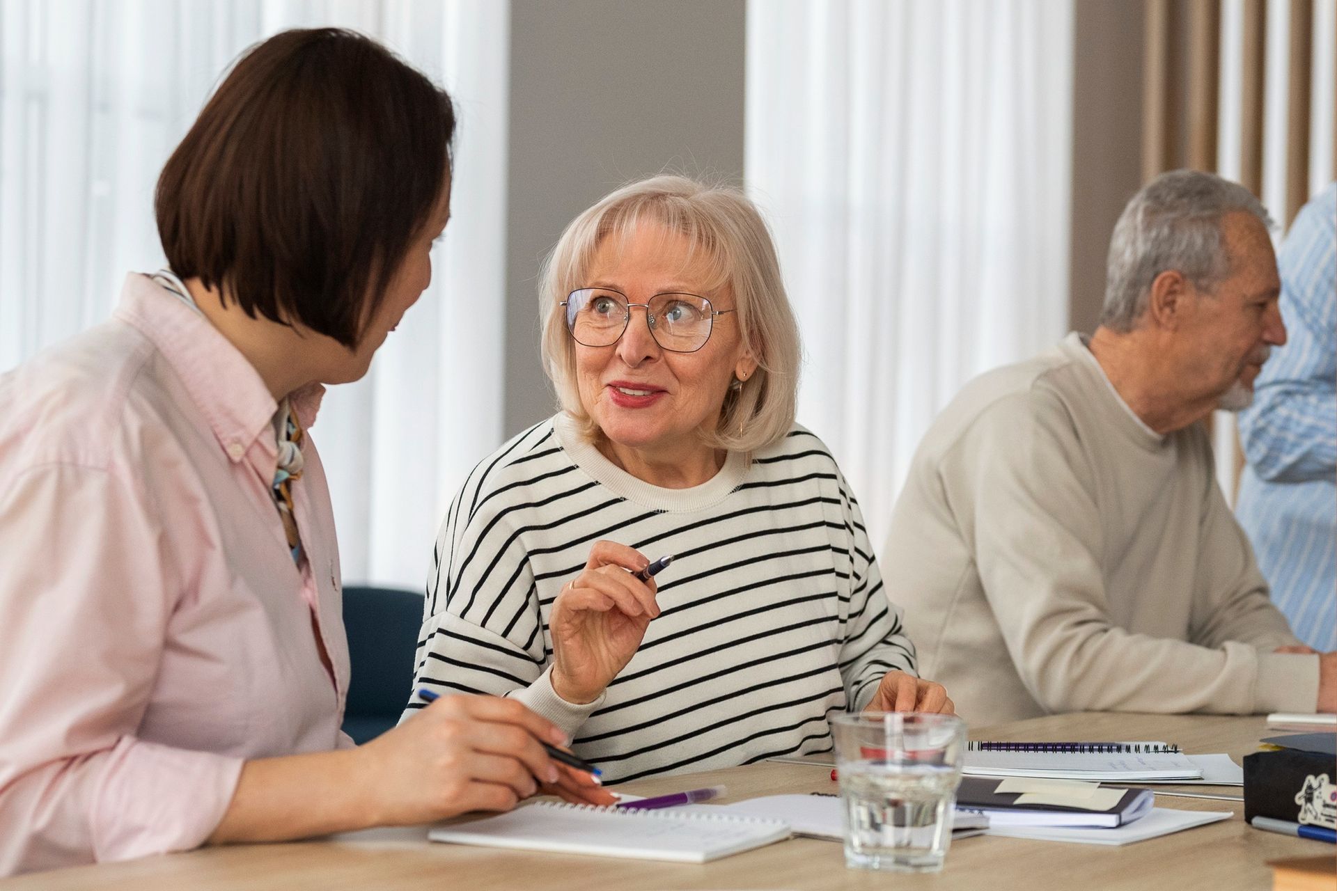 People talking at a meeting table, with one woman gesturing and others listening.