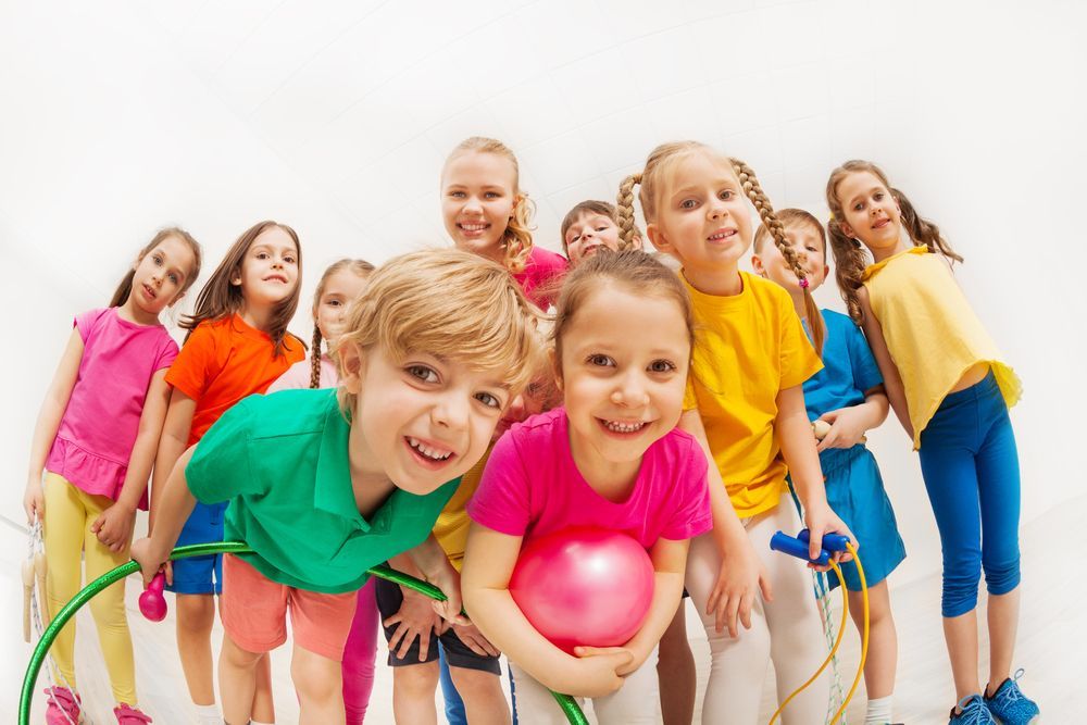 A group of children are sitting on the floor playing with hula hoops.