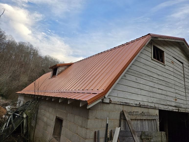 Old barn with a red metal roof and weathered wood siding in a rural setting