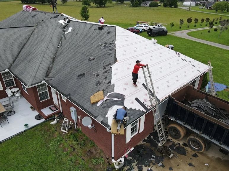 Workers repair roof damage after a truck crash into a house's side wall.