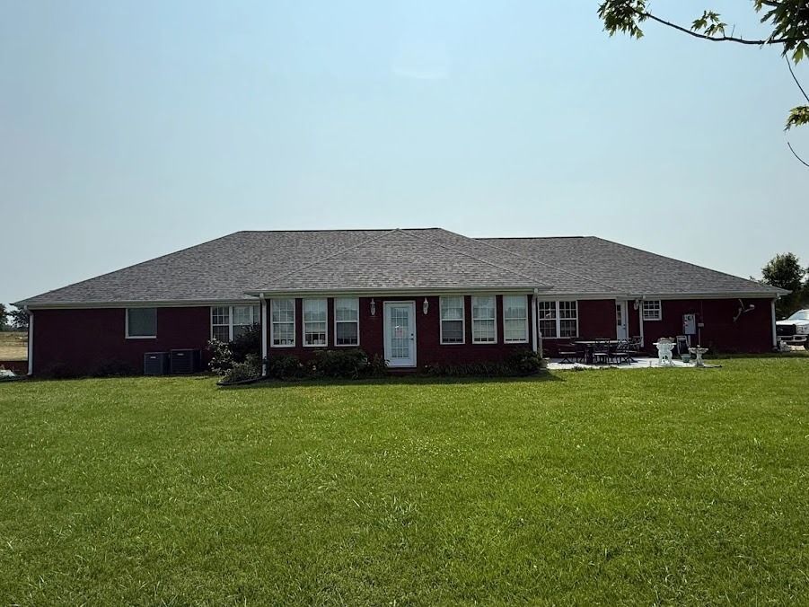 Single-story brick house with a large green lawn and clear sky