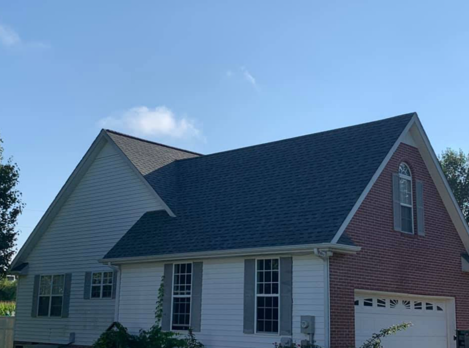 Suburban house with gray siding, blue roof, and red garage gable under a clear sky