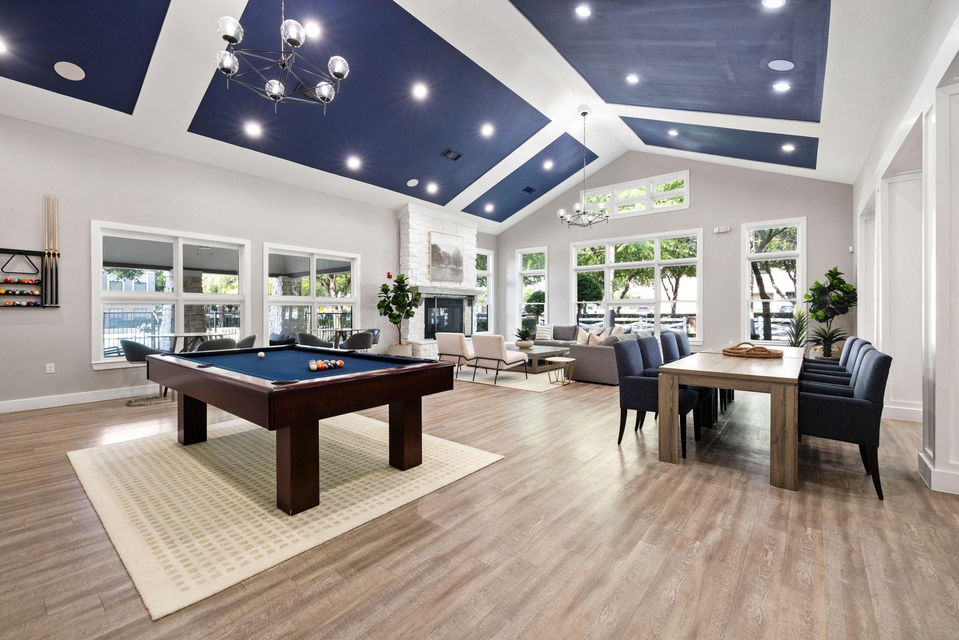 Spacious game room with pool table, seating area, and blue vaulted ceiling with chandelier lights