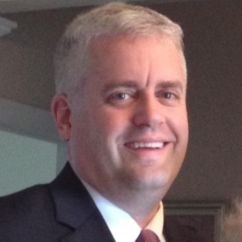 A man in a suit and tie smiles for the camera