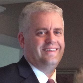 A man in a suit and tie smiles for the camera