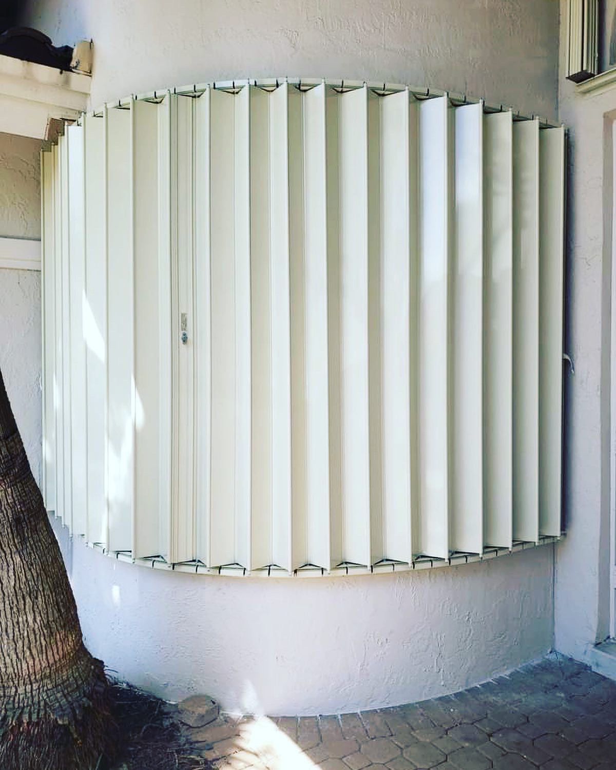 A white accordion door is on a curved wall