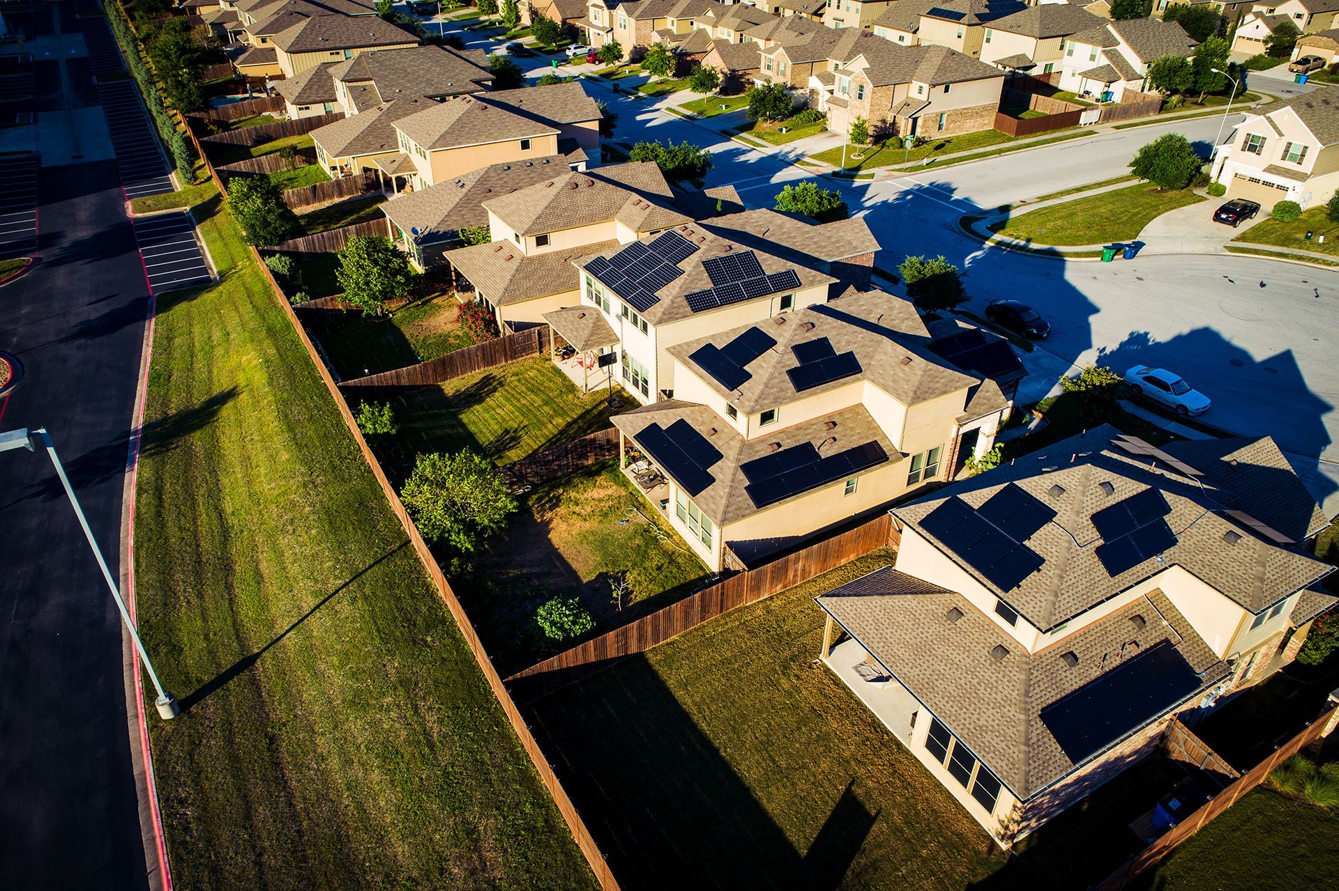 An aerial view of a residential neighborhood with solar panels on the roofs of houses