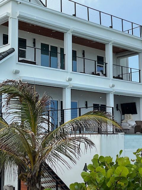 A large white house with a balcony and palm trees in front of it