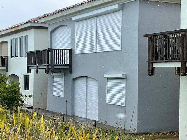 A white building with shutters on the windows and a balcony
