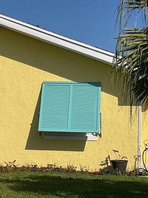 A yellow house with blue shutters on the windows
