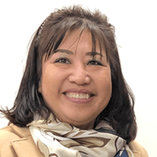A woman wearing a scarf and a coat is smiling for the camera.