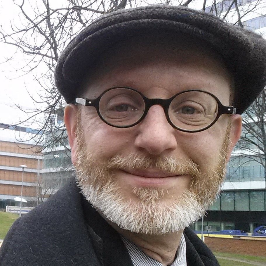 A man with a beard wearing glasses and a hat
