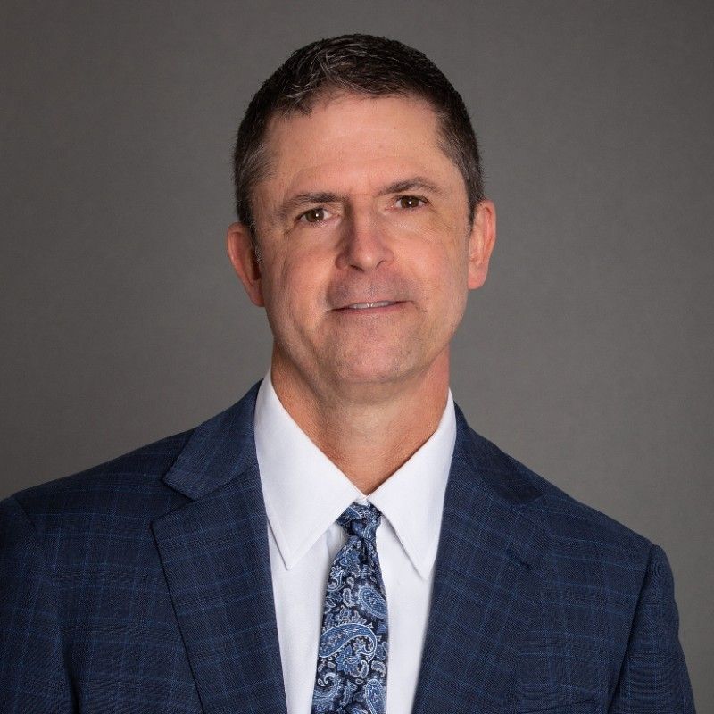A man in a suit and tie is smiling for the camera.