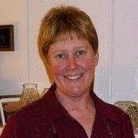 A woman in a red shirt is smiling for the camera.