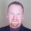 A man with a beard is wearing a suit and turtleneck.