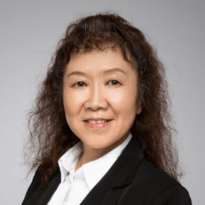 A woman with curly hair is wearing a black jacket and white shirt.