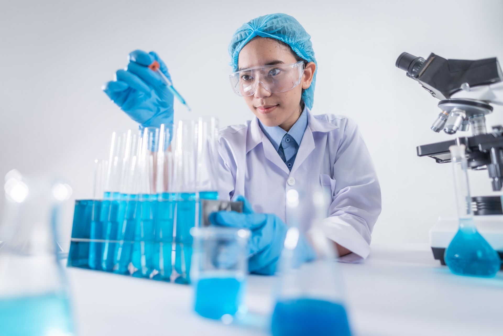 A female scientist is pouring liquid into test tubes in a laboratory.