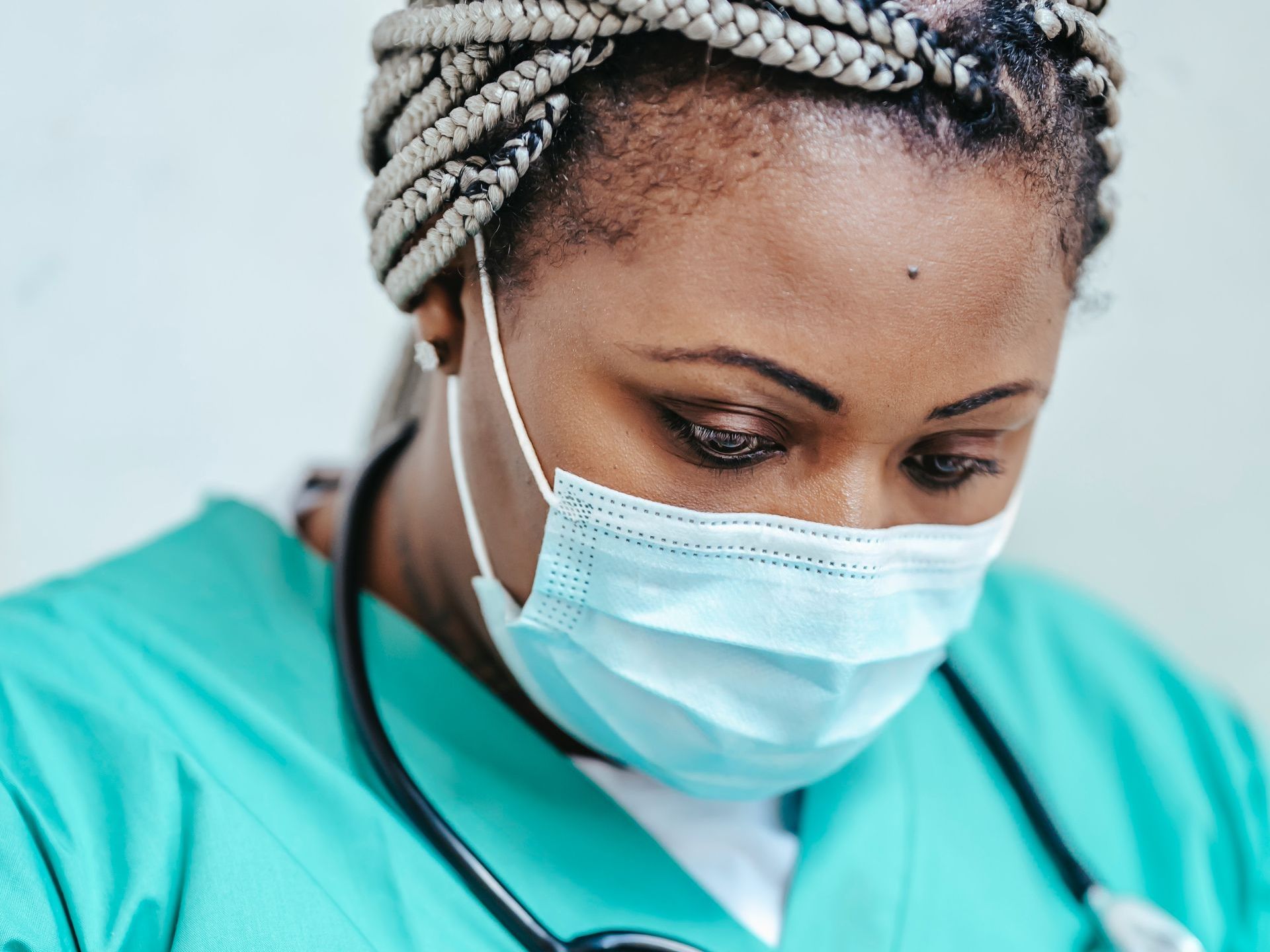 A nurse wearing a mask and a stethoscope around her neck.