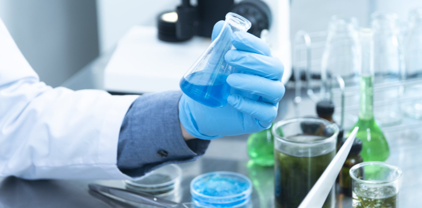 A scientist is pouring liquid into a beaker in a laboratory.